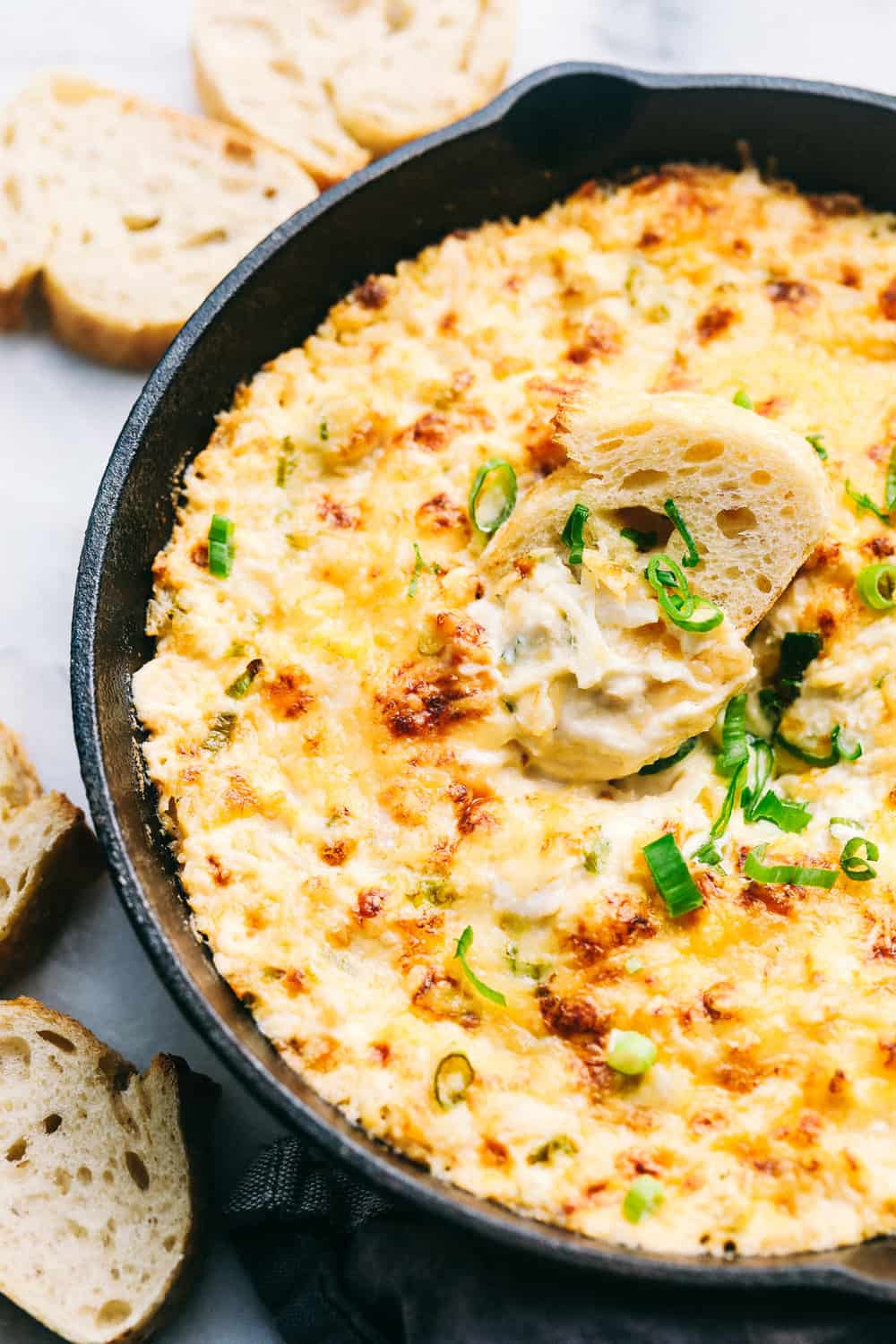 Hot Crab Dip in a metal pan with sliced bread on the side. 