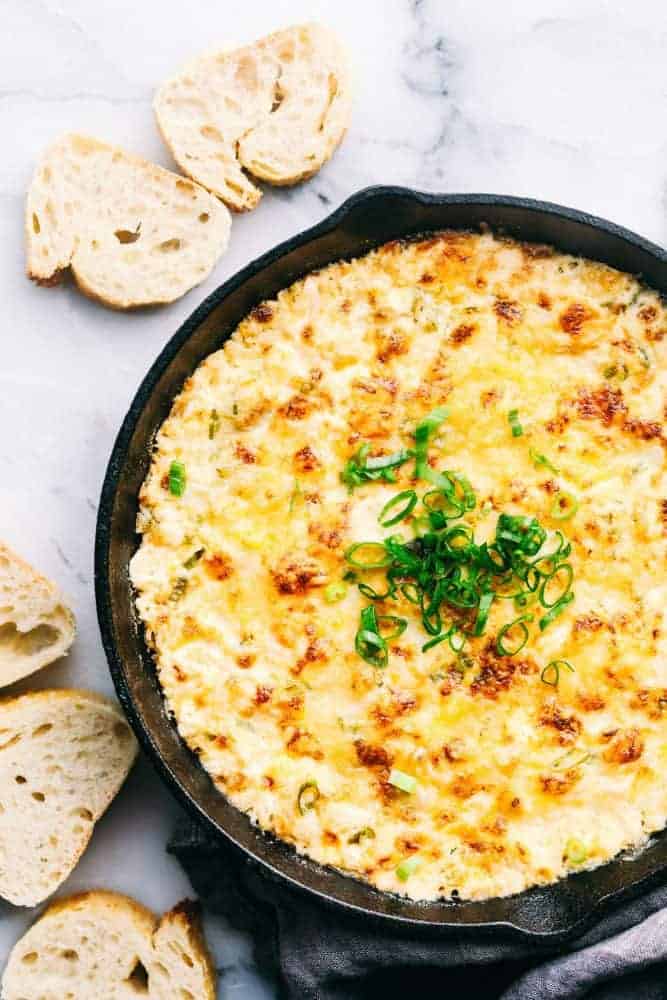 Hot Crab Dip in a metal pan with sliced bread on the side. 