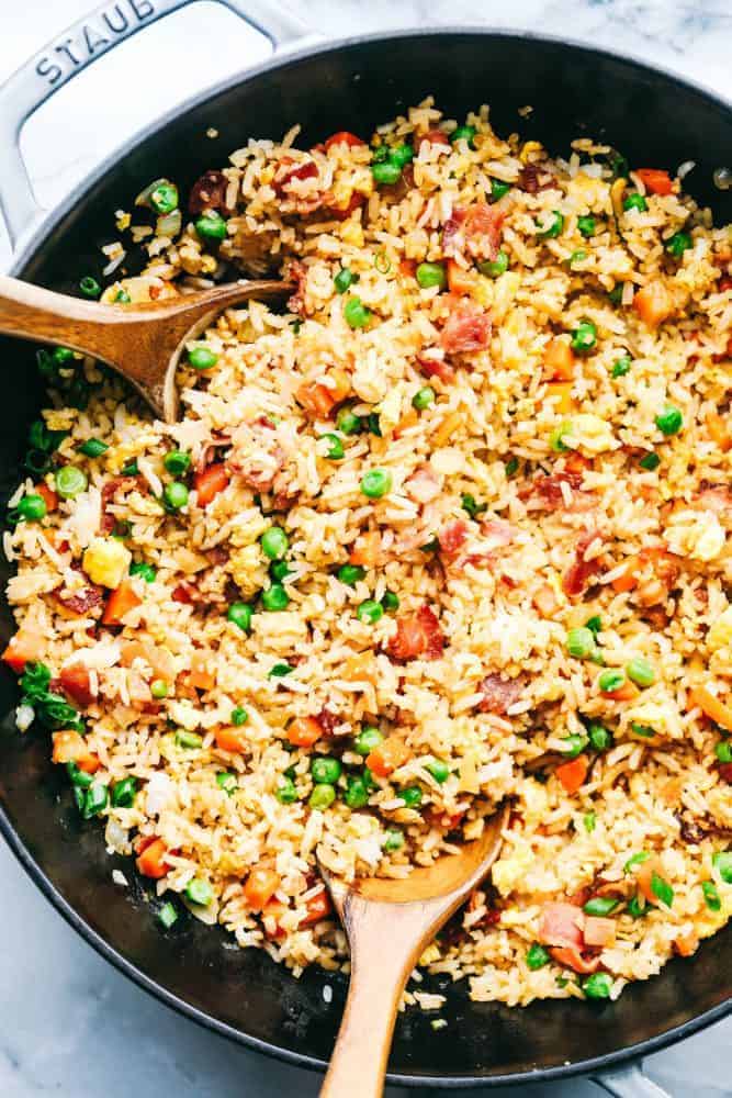 Bacon Fried Rice in a skillet with two wooden spoon. 