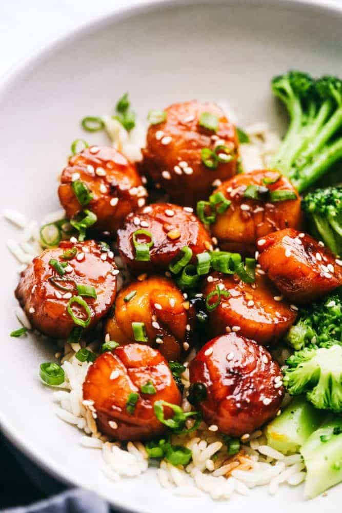 Honey Garlic Butter Scallops over white rice in a white bowl with broccoli on the side - Easy Menu Planning