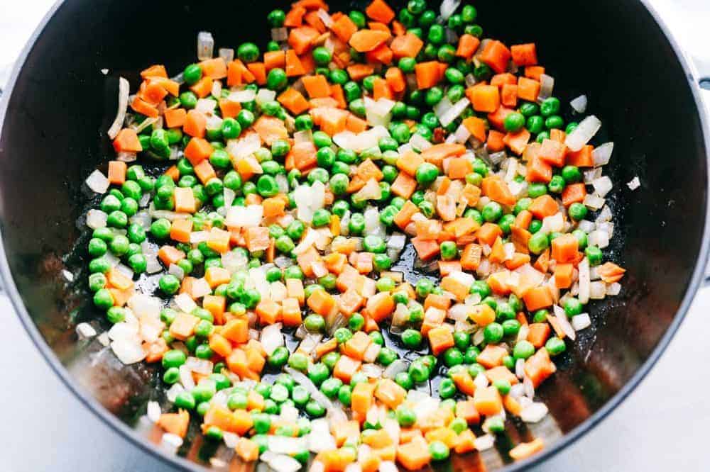 Peas and carrot mixture in a frying pan. 