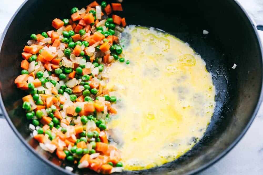Peas and carrot mixture with egg in a frying pan. 