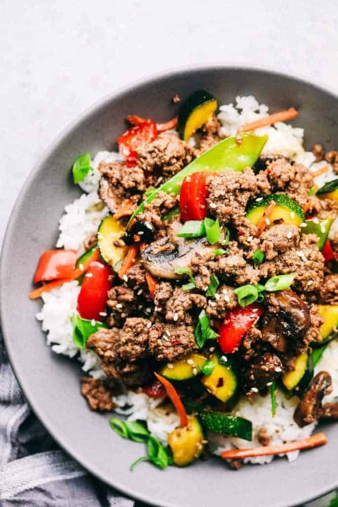 Korean ground beef over white rice in a gray bowl sitting on a countertop. 