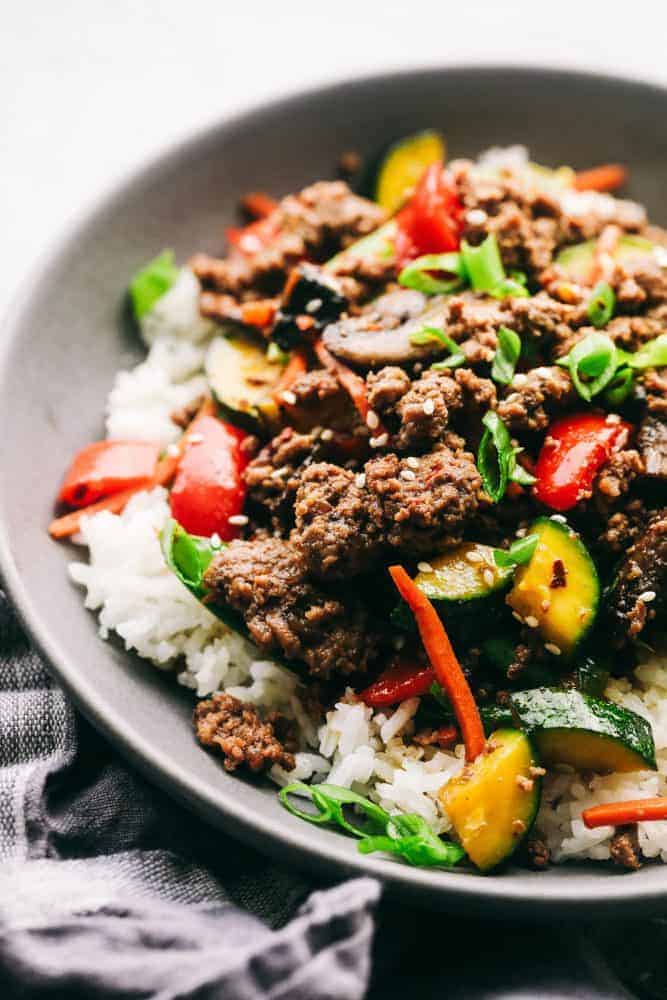 Korean ground beef stir fry over top white rice in a gray bowl. 