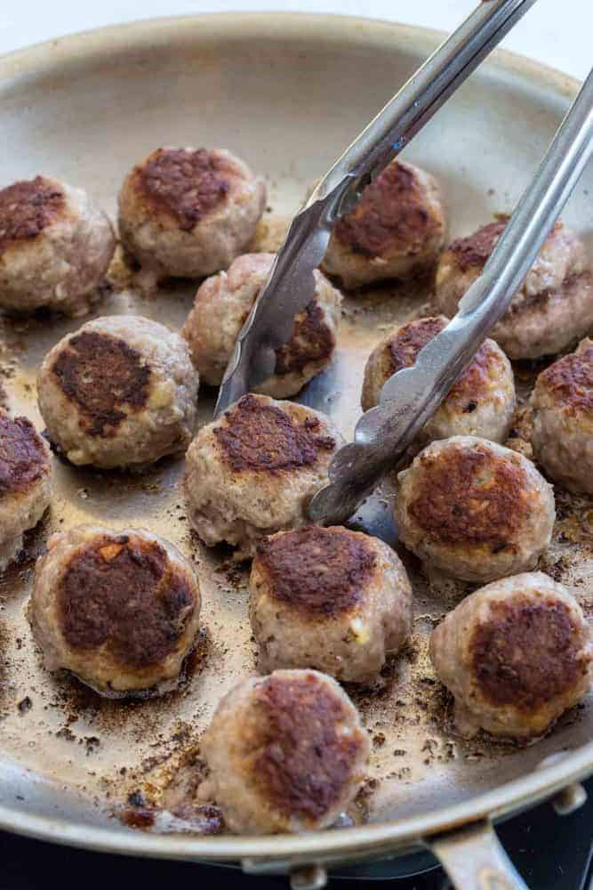 Meatballs browning in a saute pan.
