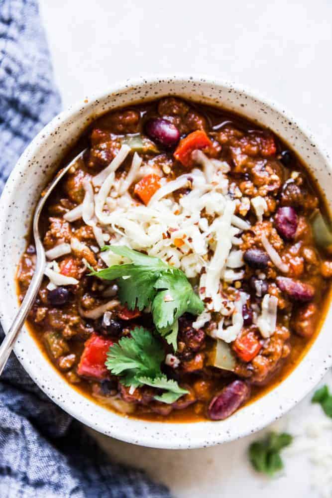 Slow cooker pumpkin chili in a white bowl with the metal spoon.