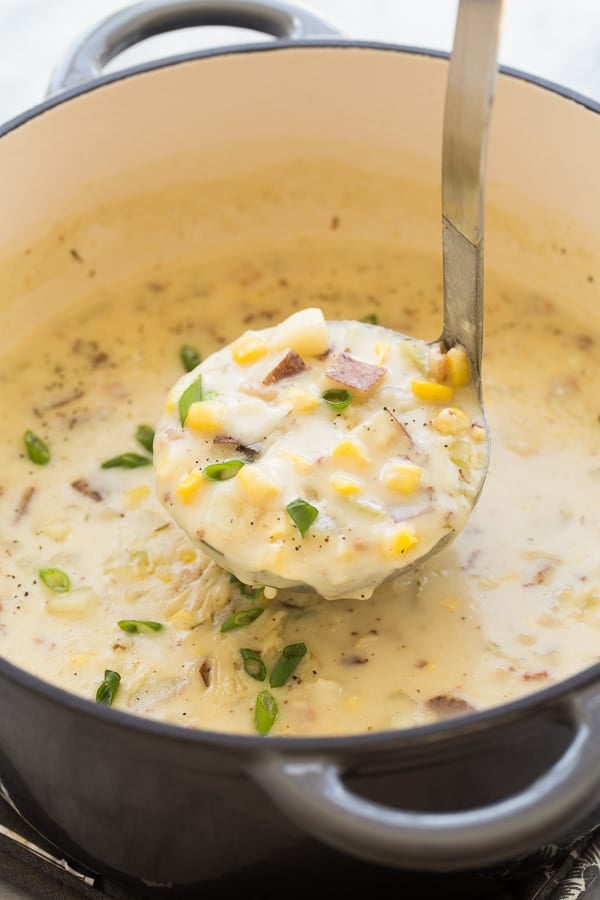 Large pot of corn chowder with a ladle removing some. 