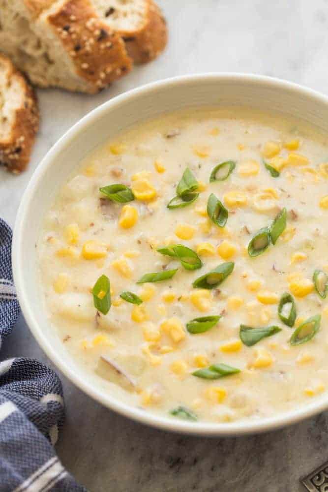 Large bowl of corn chowder with bread on the side.