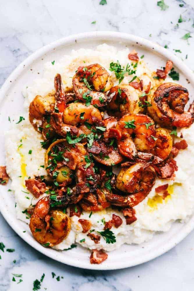 Cajun garlic shrimp and grits on a white plate.