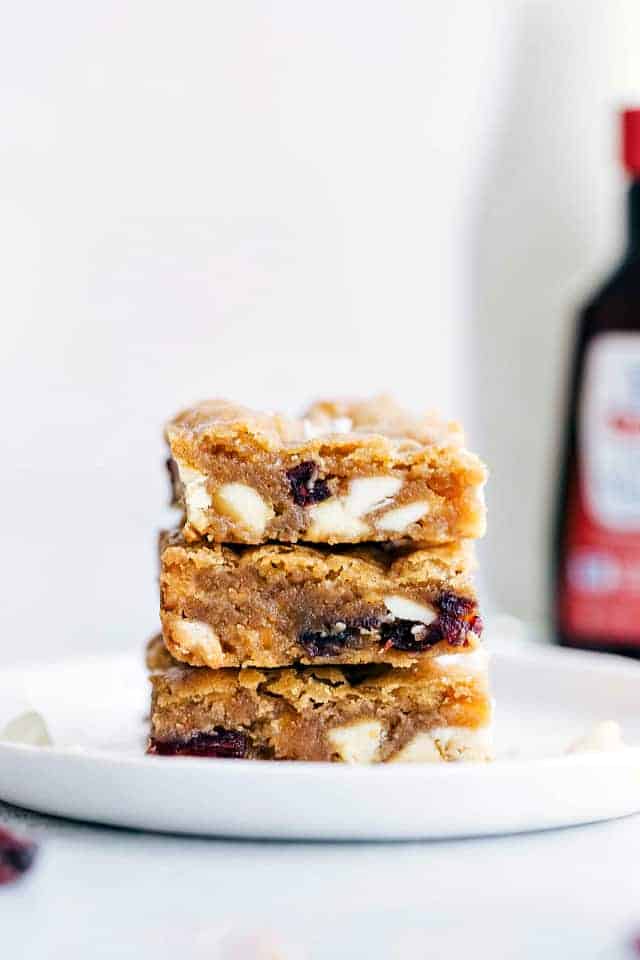 Three white chocolate cranberry Blondies stacked on top of each other to show the chunks of white chocolate cranberry in the middle.