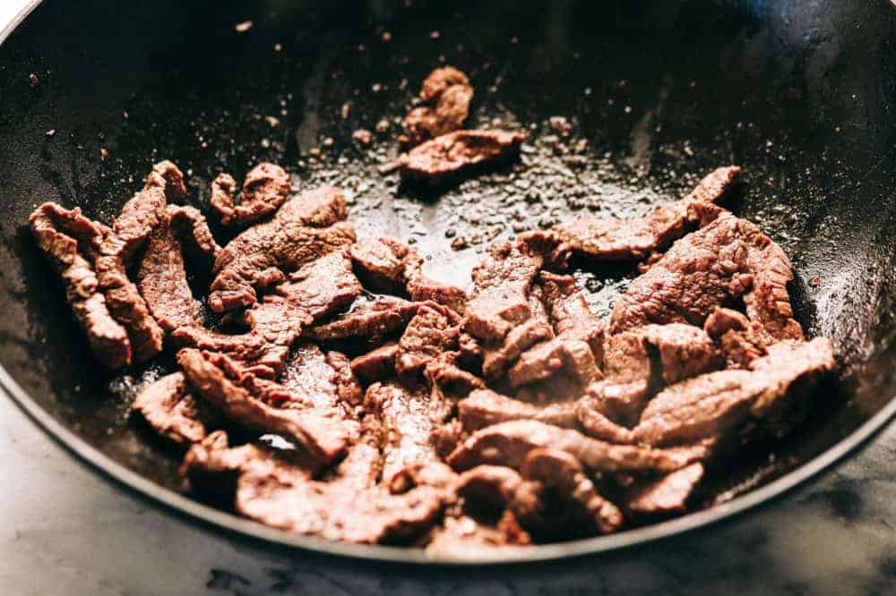 Garlic beef being cooked in a skillet.