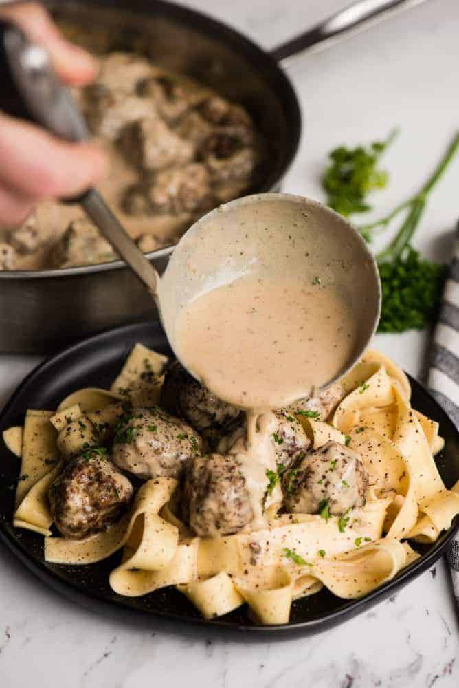 Swedish meatball pasta having this creamy sauce poured over top from the ladle.