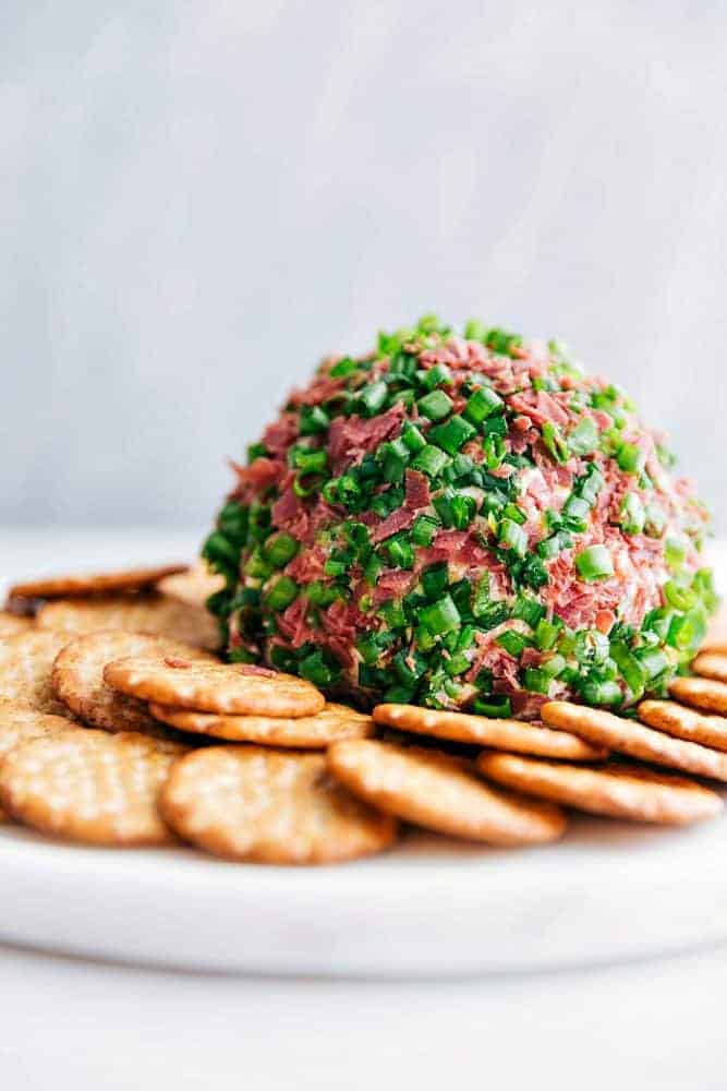 Chipped beef cheese ball on a white plate with crackers surrounding it.