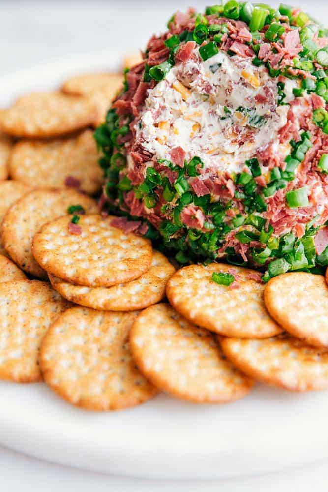 Chipped beef cheese ball on a white plate with crackers surrounding it.