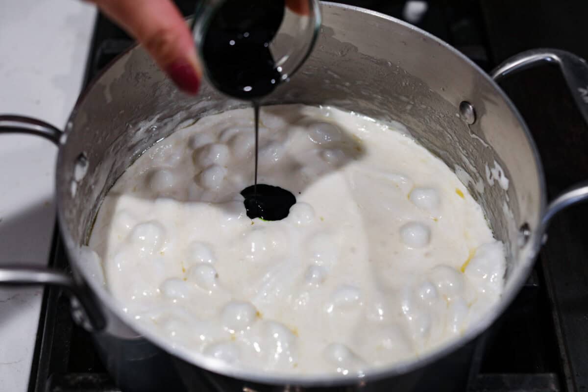 Angle shot of someone pouring in the food coloring into the marshmallow mixture. 