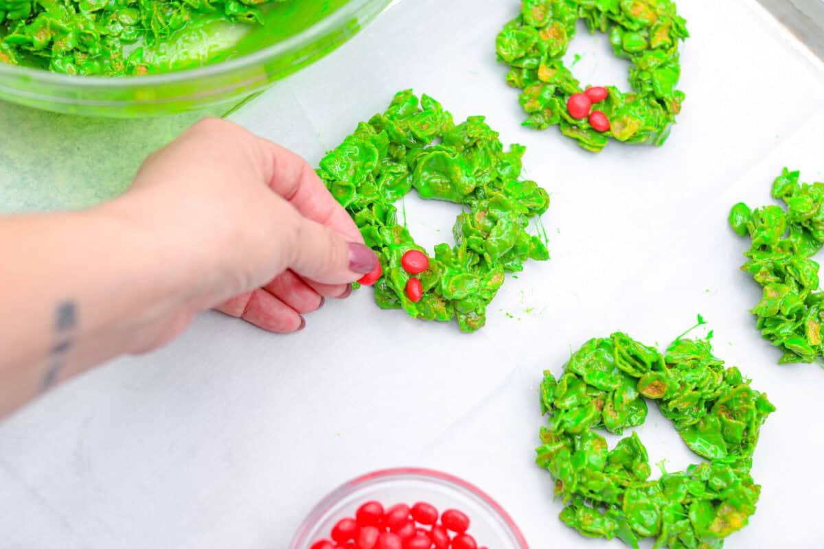 Overhead shot of someone placing the cinnamon candy on the wreaths. 