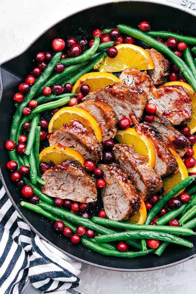 Roasted cranberry orange pork tenderloin with green beans in a skillet.