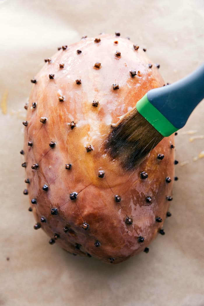 Ham that is scored and being brushed with a sweet glaze mixture