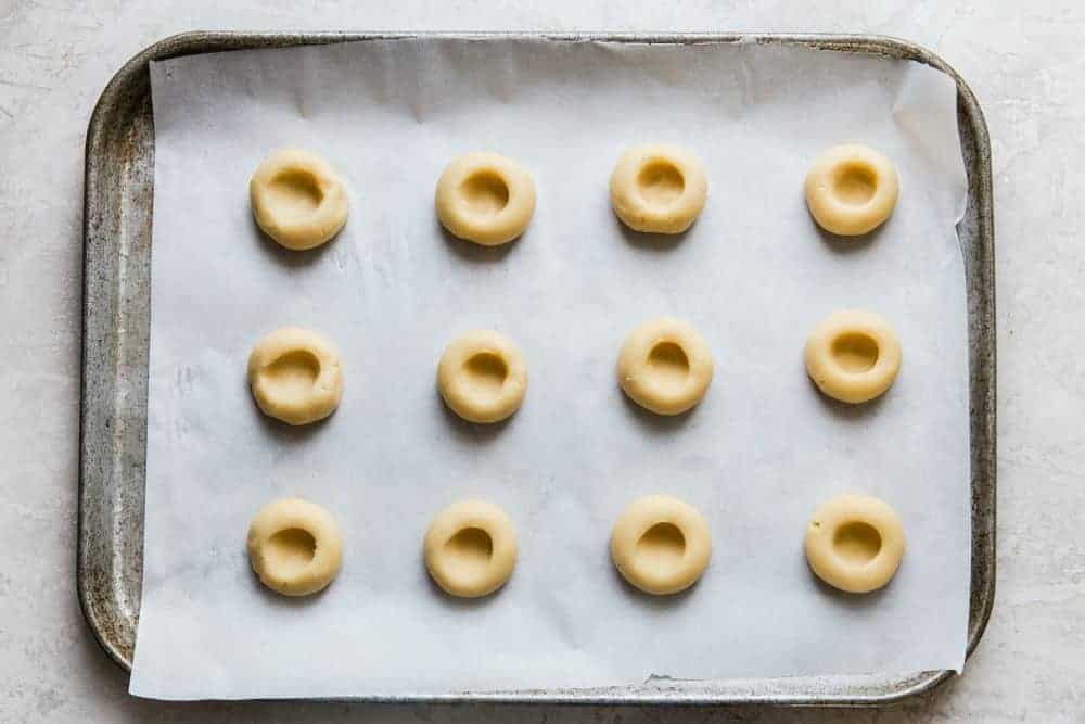 Almond thumbprint cookies on a cookie sheet.