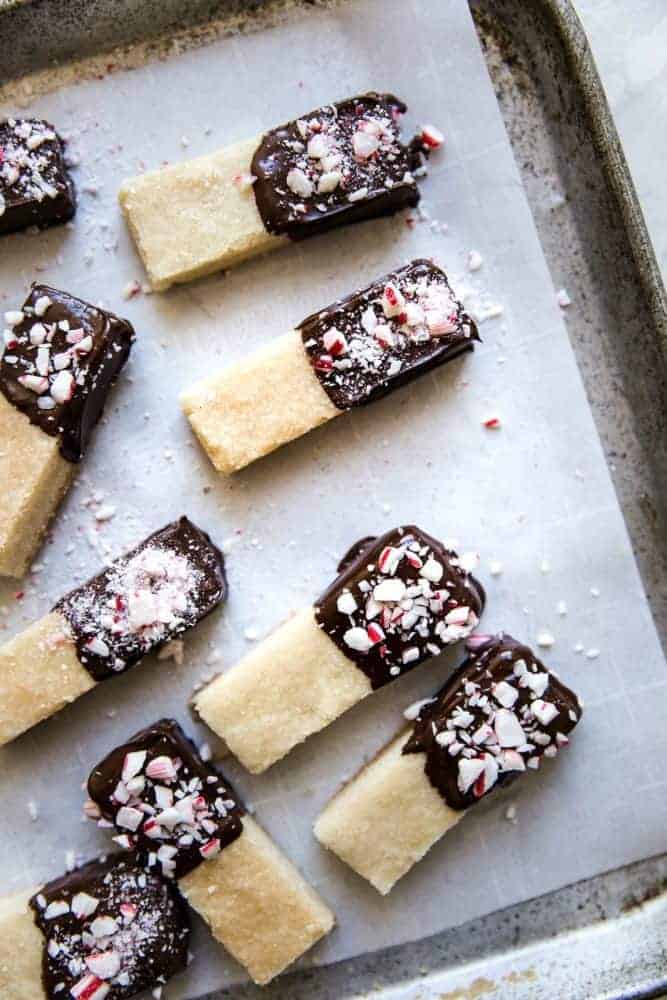 Chocolate peppermint dipped shortbread cookies on parchment paper on a cooking sheet.
