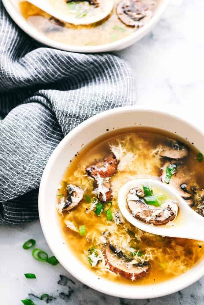 Egg drop soup in a bowl with a spoon scooping some up.