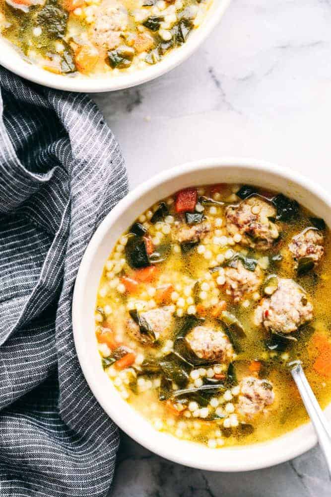 Two white bowls full of Italian wedding soup.