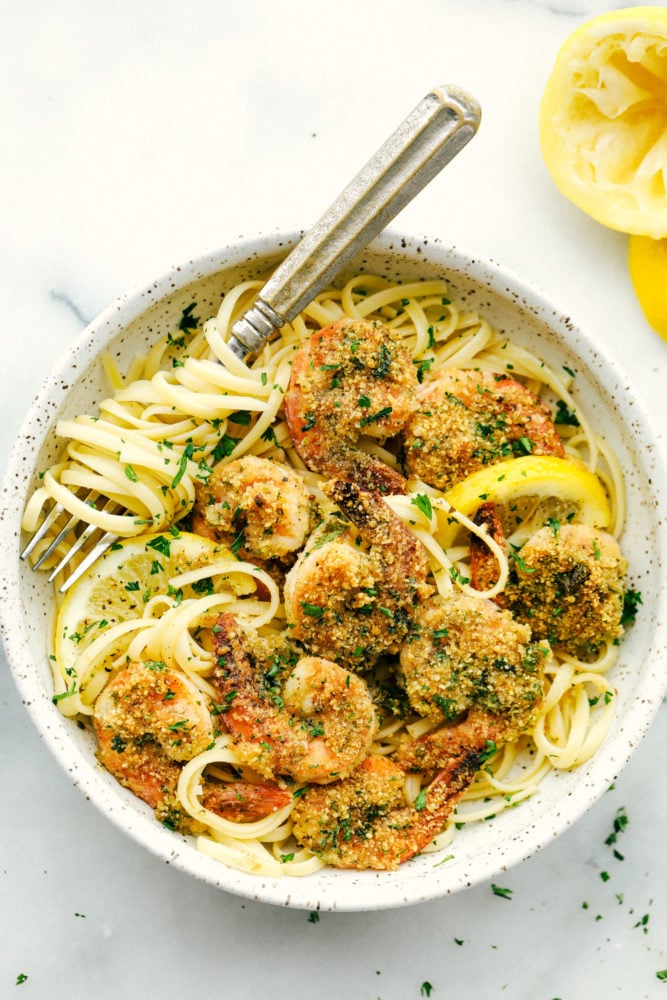 Limón camarones ajo en un tazón sobre fideos linguini superior con un tenedor dentro del tazón. 