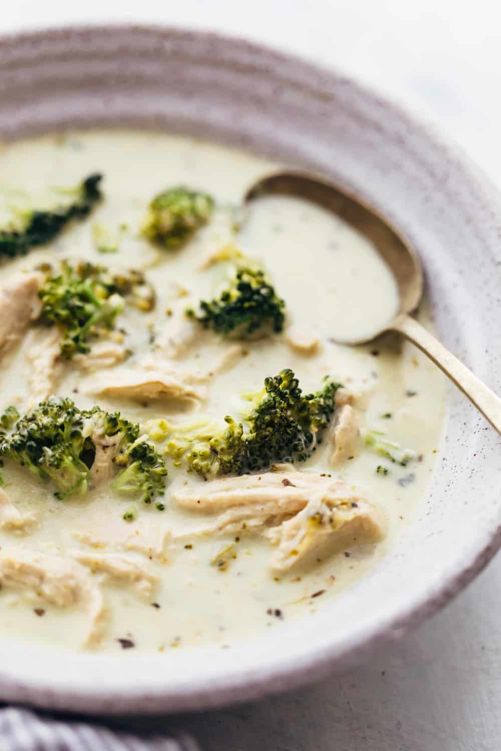 Closeup of creamy chicken broccoli soup in a bowl with a spoon