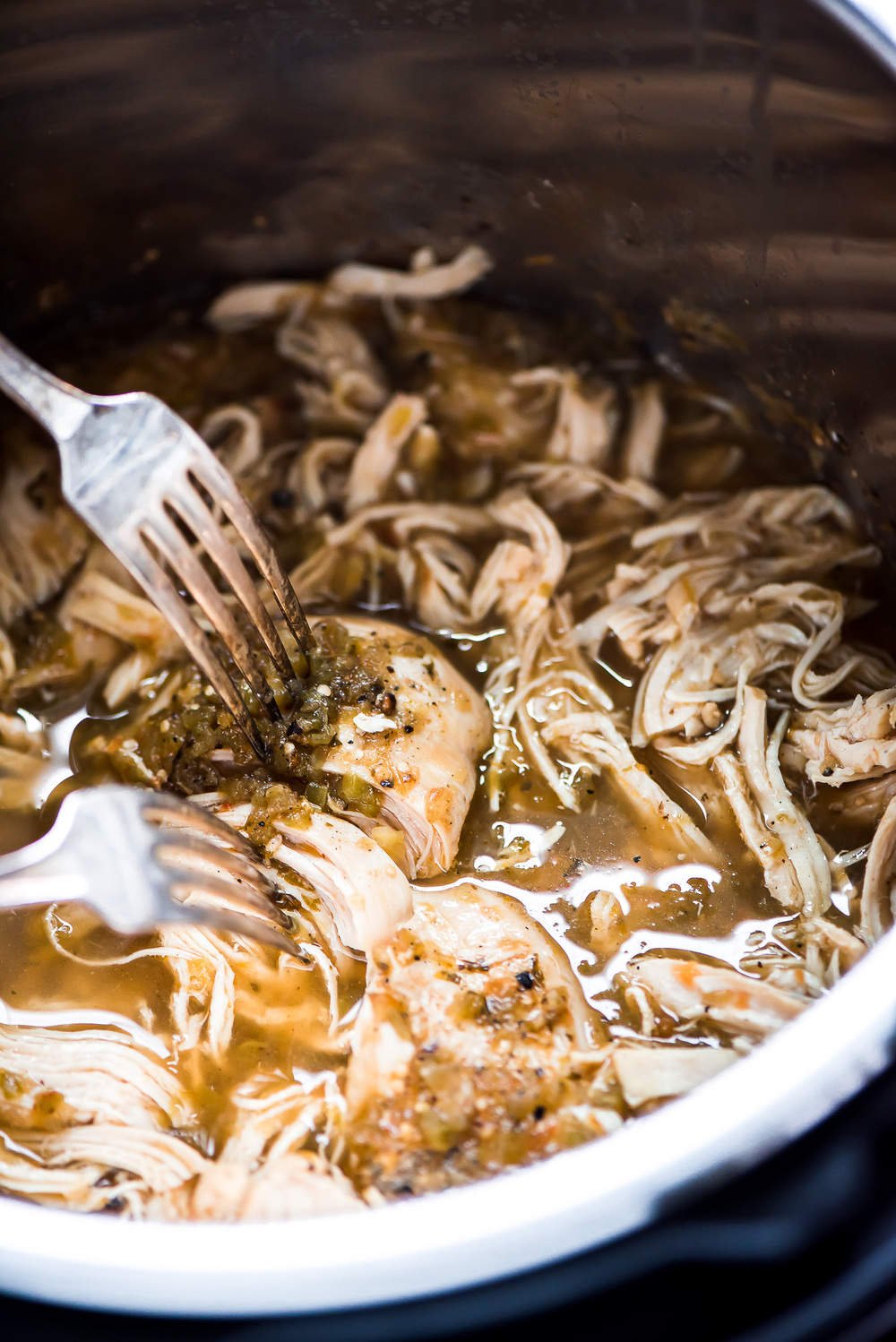 Shredding cooked chicken with 2 forks.