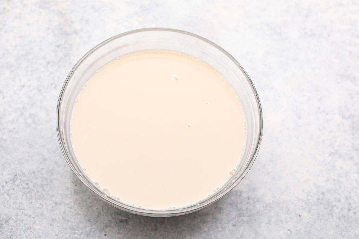 Overhead shot of the three milks mixed together in a glass bowl. 