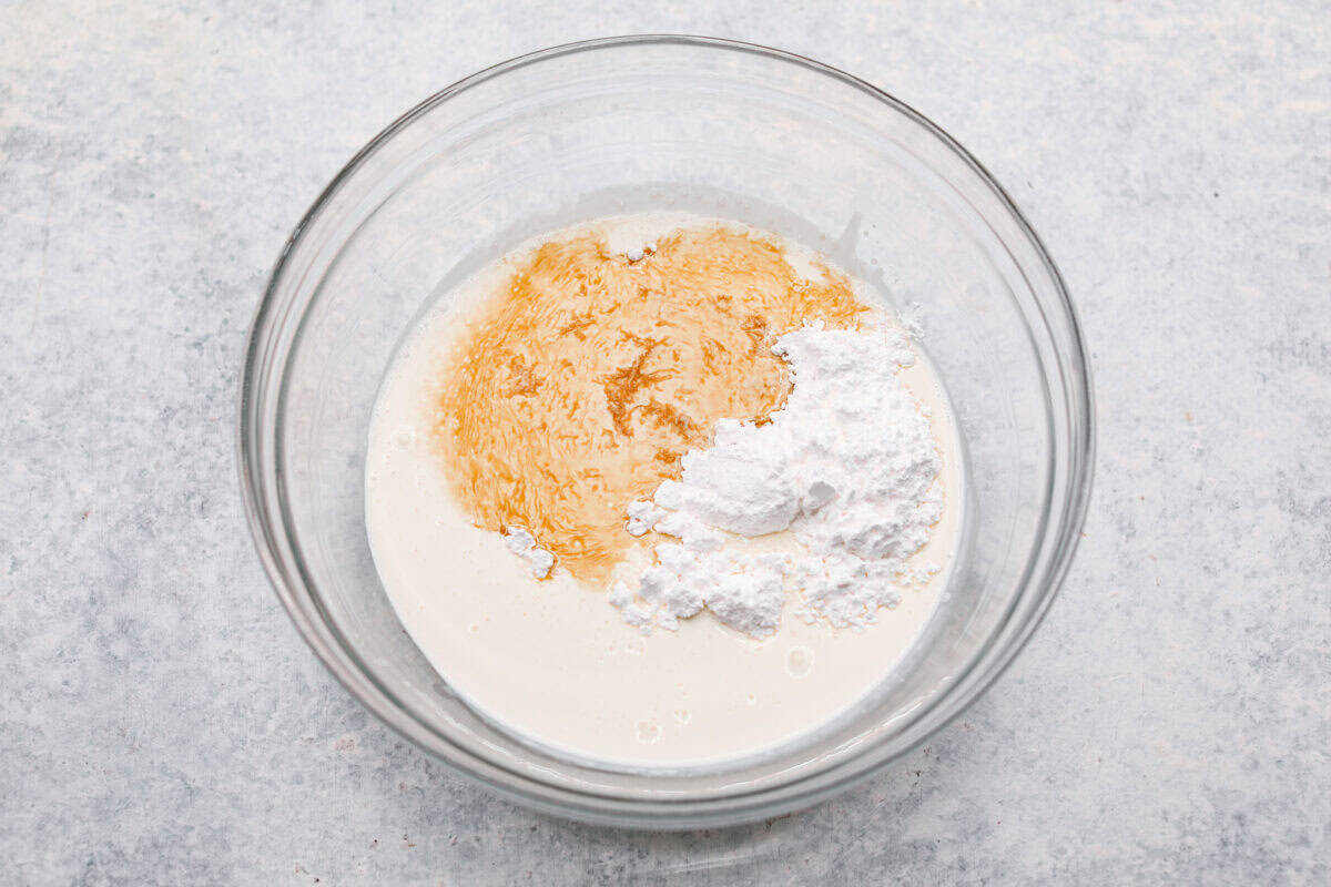 Overhead shot of whipping cream powdered sugar and vanilla in a bowl. 