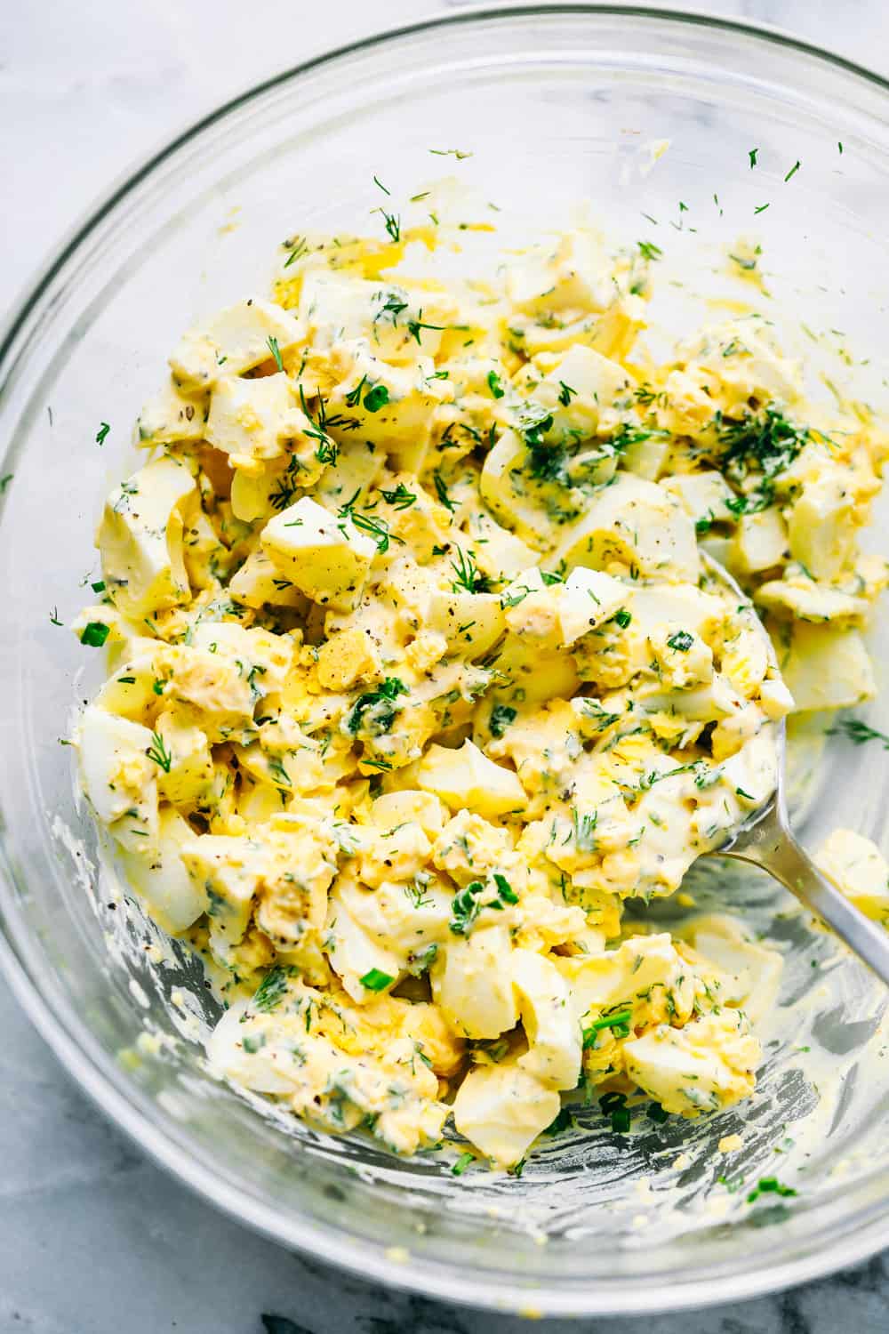 Mixing the egg salad in a clear bowl.