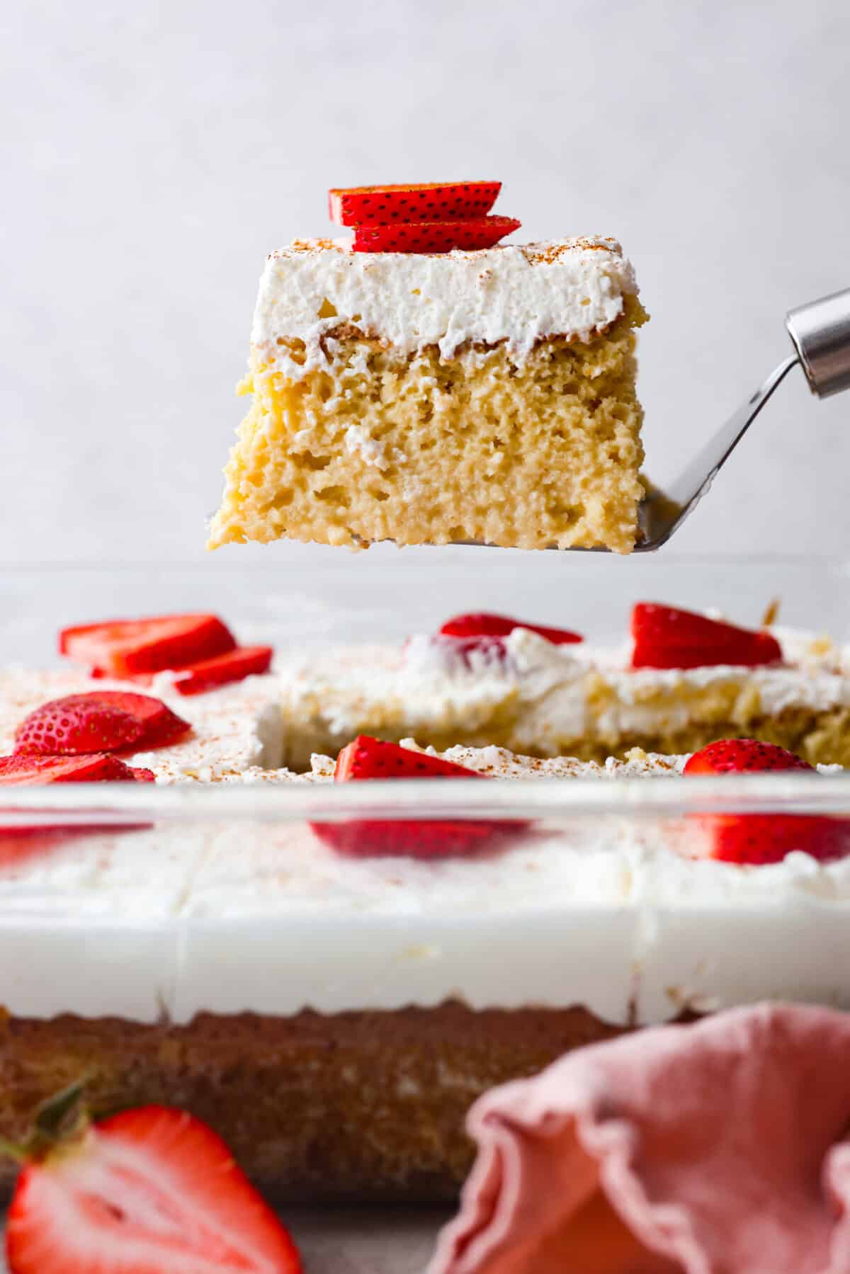 Side shot of a slice of tres leches cake being lifted out of the pan.