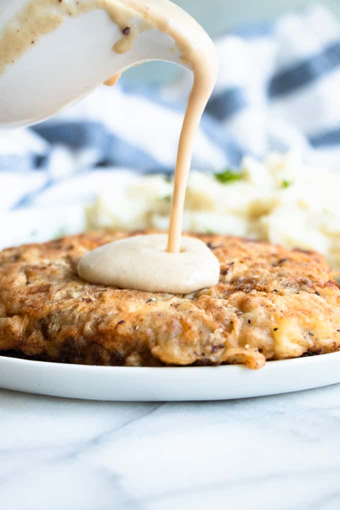 Pouring gravy over chicken fried steak.