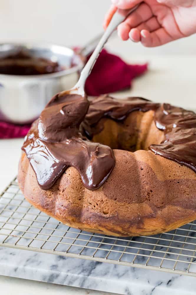 Chocolate ganache being poured over the cake.