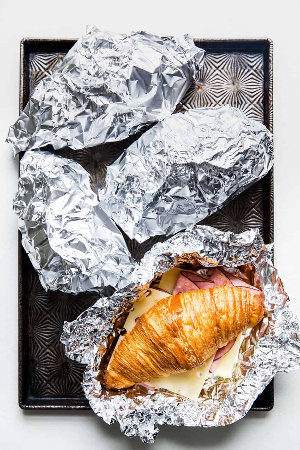 Wrapping a Monte Cristo Croissant Sandwich in tin foil.