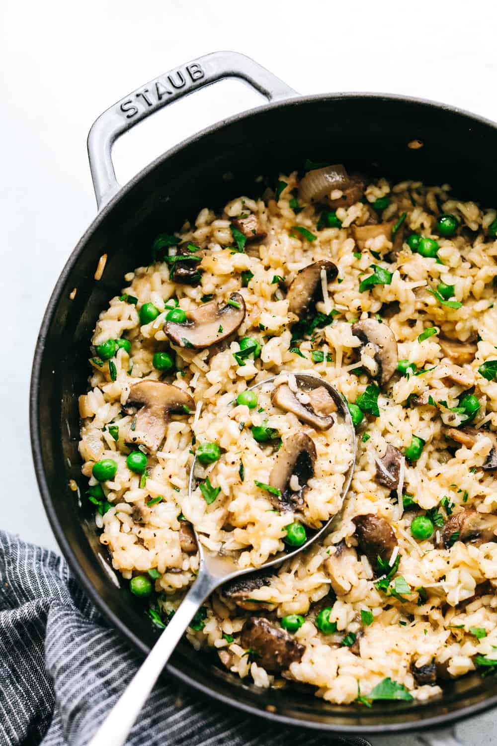 Mushroom risotto close up in a black pan with a spoon.