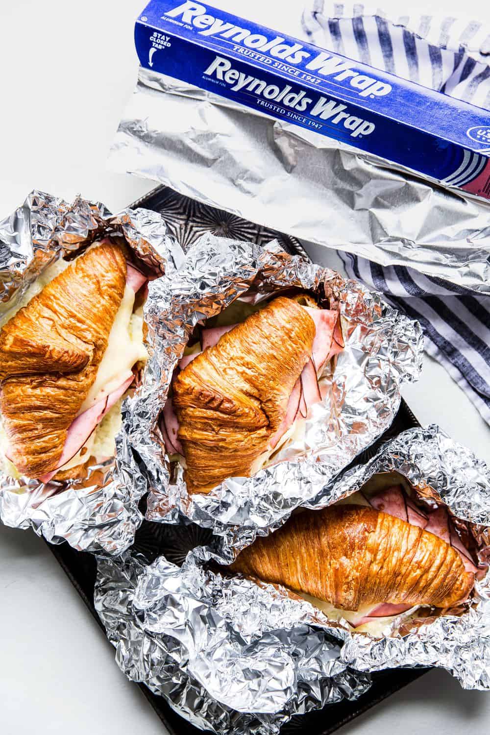 Monte Cristo Croissant Sandwich in tin foil wrappers.