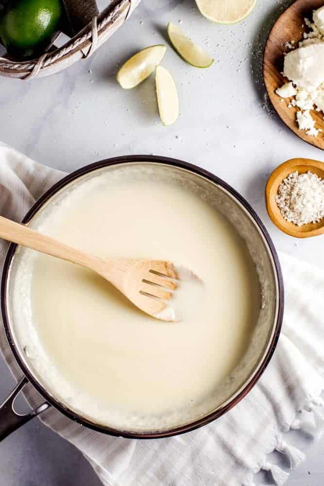 Making queso in a pot and stirring with a wooden spoon.