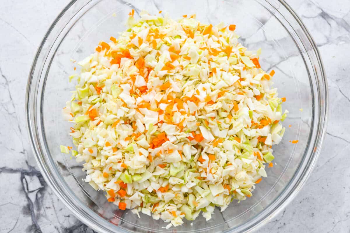 Overhead shot of chopped carrots and cabbage in a mixing bowl.