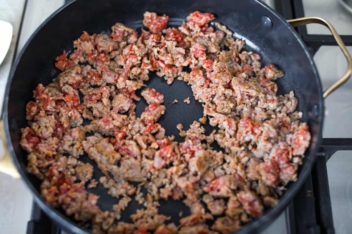 Italian sausage cooking in a skillet.