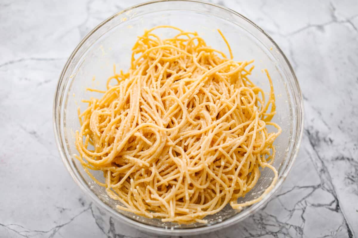 Overhead shot of noodles mixed with the egg, butter and cheese mixture. 