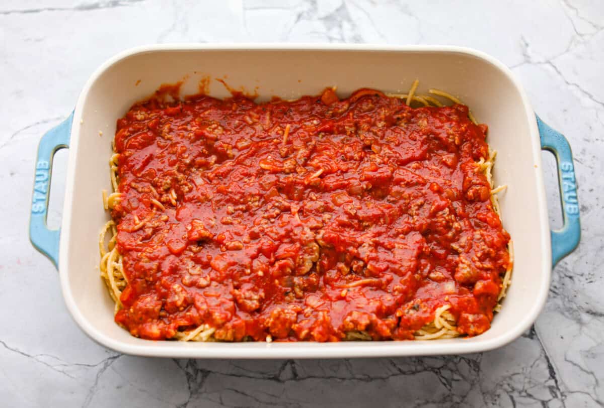 Meat sauce layered on top of the noodles in the baking dish. 