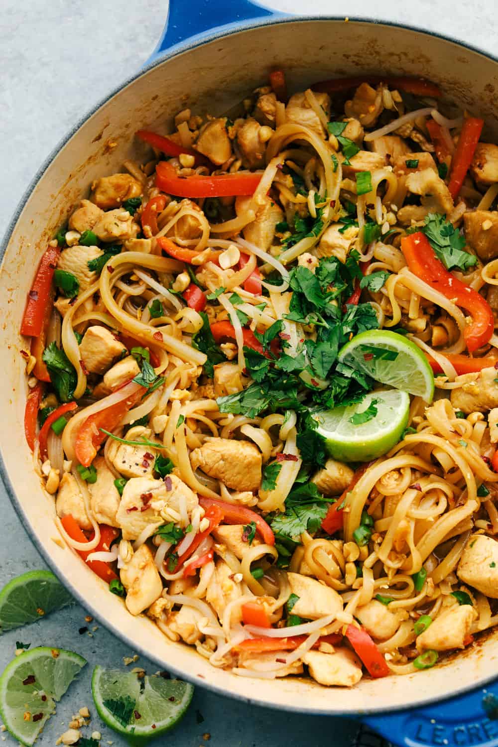 Pad thai in a being mixed together in a large dutch pan. 