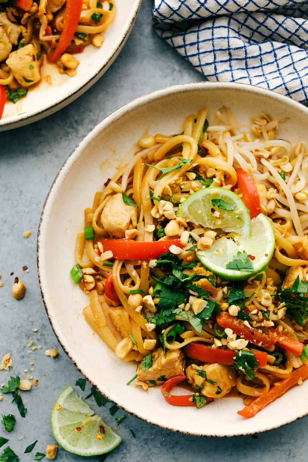 Pad Thai in a dish with lime wedges and garnished with cilantro. 