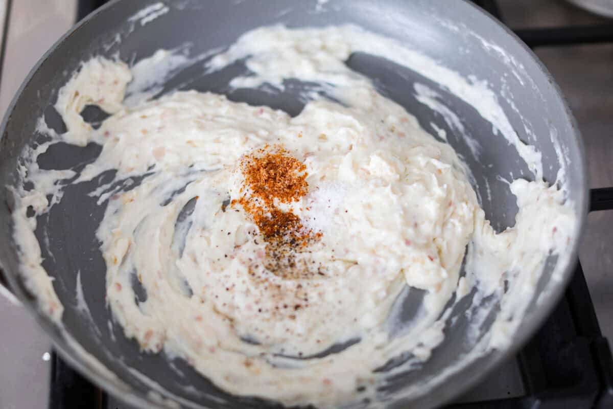 Fifth photo of the cheese and seasonings added to the creamy sauce mixture.