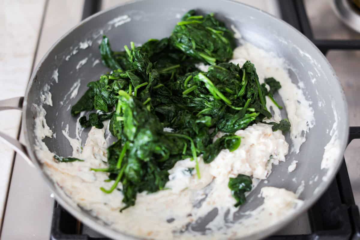 Sixth photo of the cooked spinach stirring into the creamy mixture.