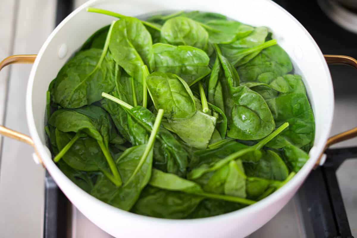 First photo of the spinach blanching in a pot.