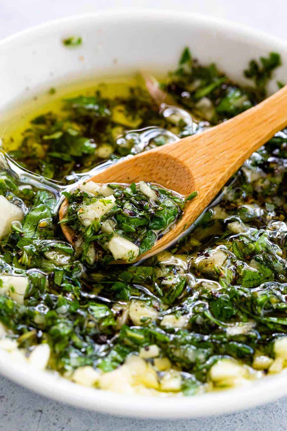 wooden spoon mixing a herb marinade