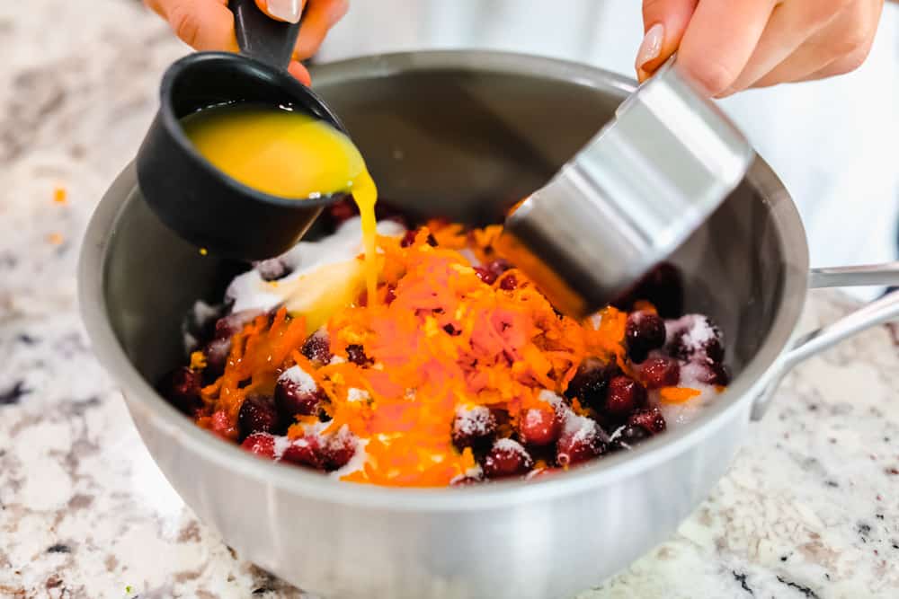 Cranberries being mixed together with sugar, orange juice and water